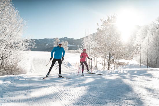Langlaufpärchen bei sonnigen Winterwetter auf der Loipe Langlaufpärchen bei sonnigen Winterwetter auf der Loipe