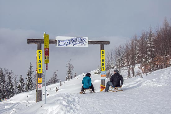 Starting point of the Hirscheckblitz toboggan run with tobogganers in the foreground Starting point of the Hirscheckblitz toboggan run with tobogganers in the foreground