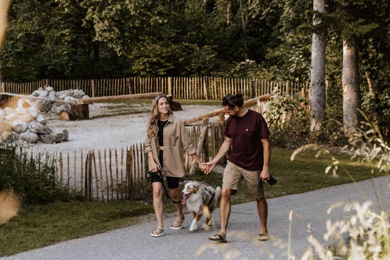 Couple with dog takes a walk around the resort, past the agility course, ideal for a relaxing evening stroll. Couple with dog takes a walk around the resort, past the agility course, ideal for a relaxing evening stroll.