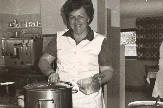 Helga, the senior manager, is cooking in the kitchen.