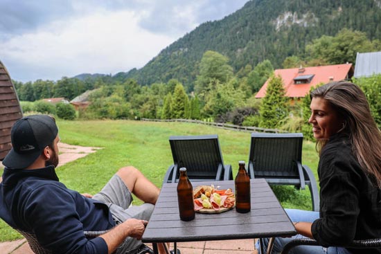 Ein Pärchen auf der Terrasse von einer Woodlodge mit Brotzeit und Bier Ein Pärchen auf der Terrasse von einer Woodlodge mit Brotzeit und Bier