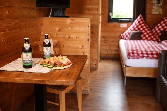 Innenansicht Woodlodge mit Detail auf Brotzeit und Bier Innenansicht Woodlodge mit Detail auf Brotzeit und Bier