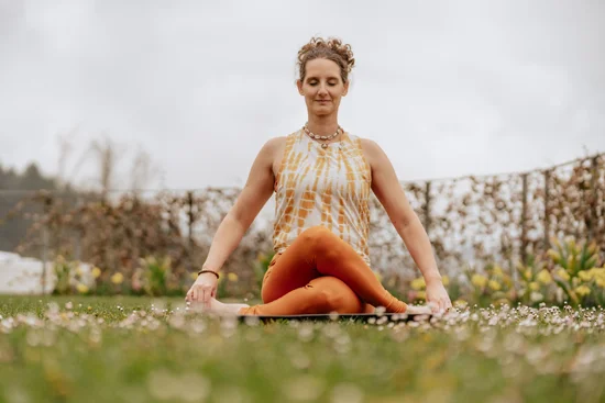 A yoga pose against a backdrop of blooming flowers, with a yoga instructor.