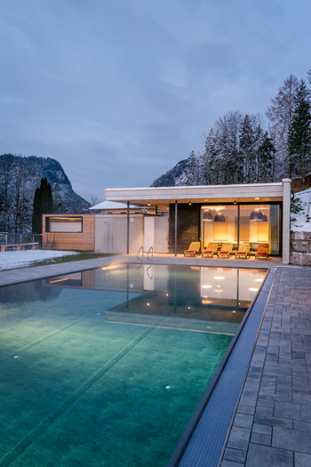 The wellness area illuminated in the evening, pool in the foreground The wellness area illuminated in the evening, pool in the foreground