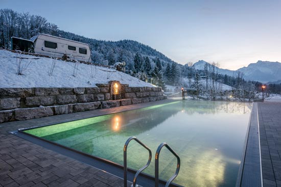 Wintercamping mit Blick auf die abendliche Bergkulisse, im Vordergrund der Infinity Pool.