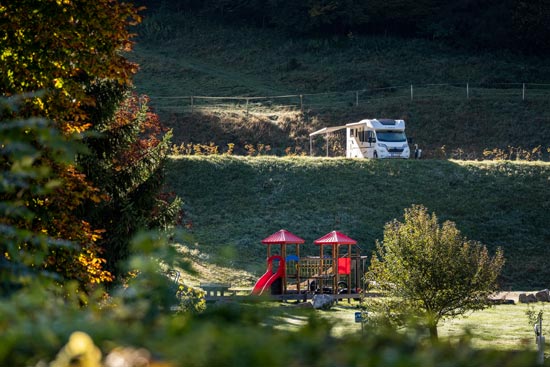 Ein Spielplatz am Campingplatz. Im Hintergrund steht ein Camper. Ein Spielplatz am Campingplatz. Im Hintergrund steht ein Camper.